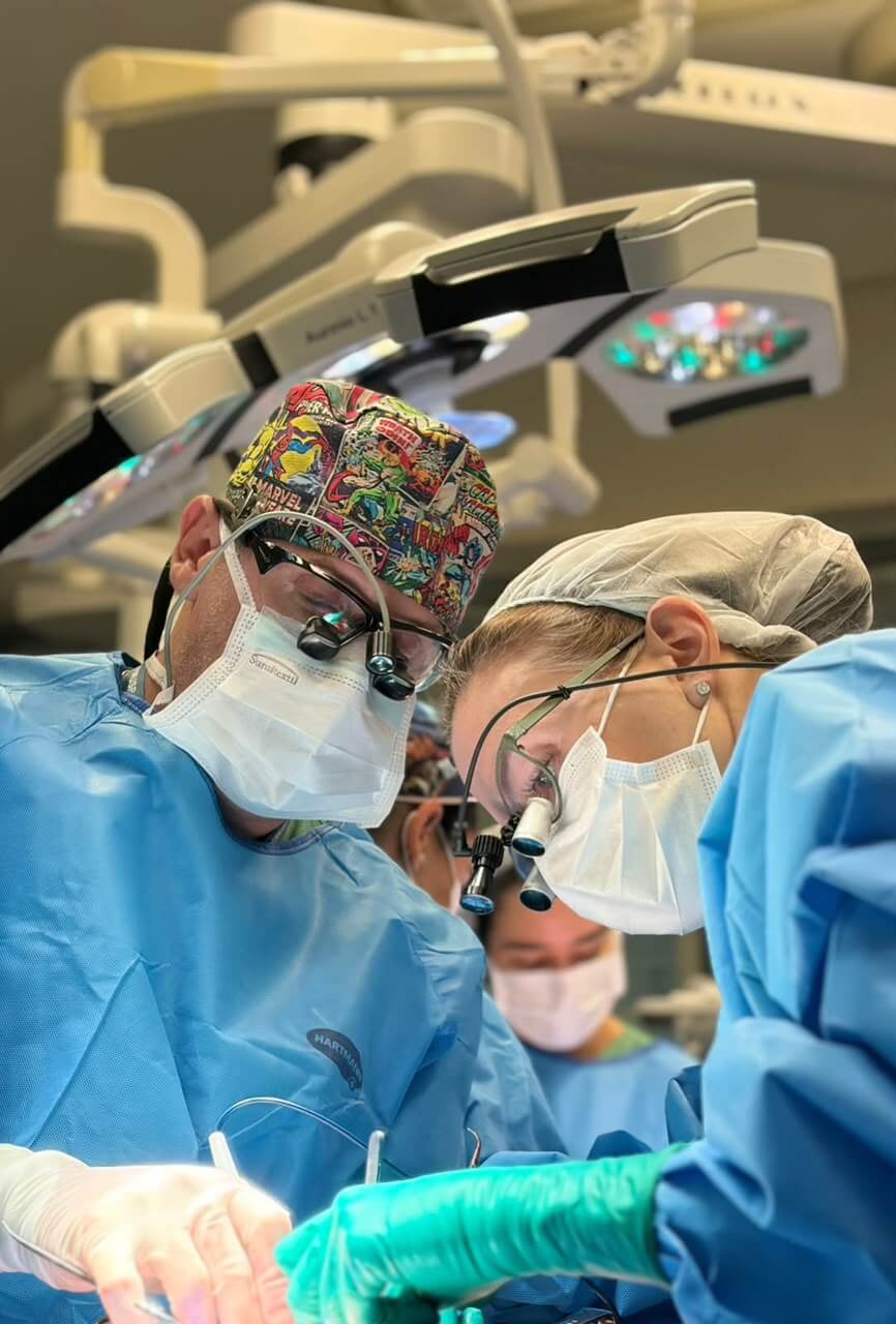 Dra. Christiana Vanni e Dr Sergio Gonçalves equipe em campo cirúrgico: o uso de lupas de amplificação microcirúrgica e instrumental especializado é imprescindível para as anastomoses vasculares de alta precisão realizadas neste caso, uso de microscópio